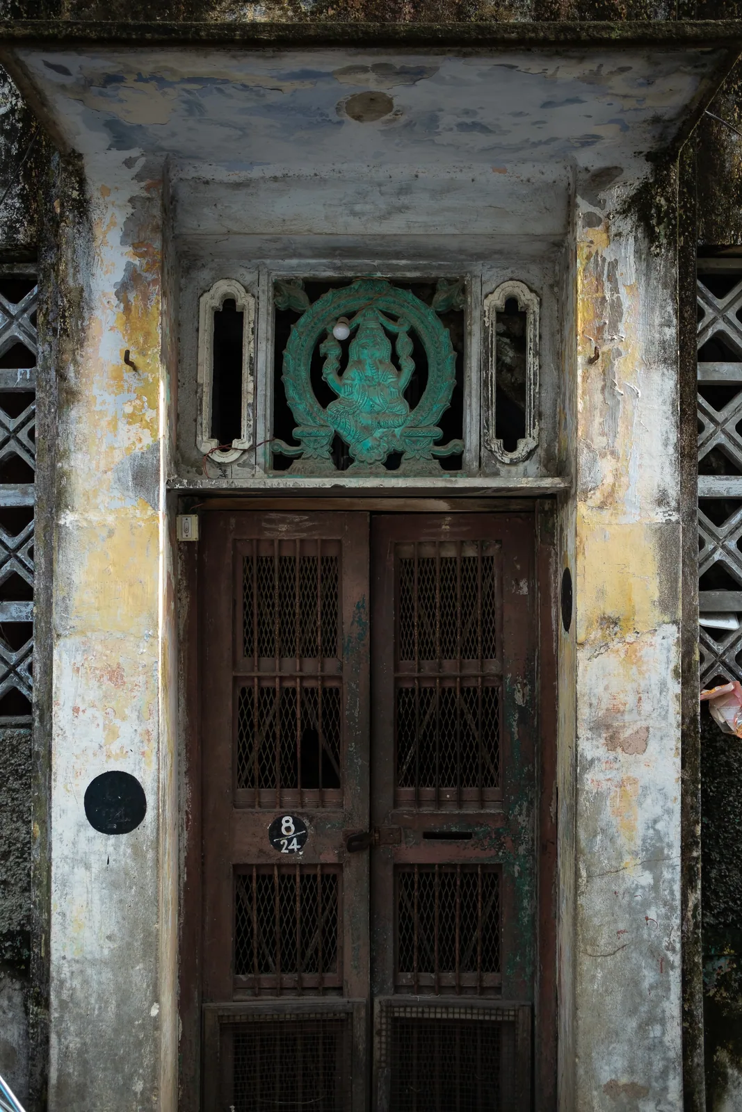 A deep doorway with a latticed door, crowned by a green ornamental fanlight.
