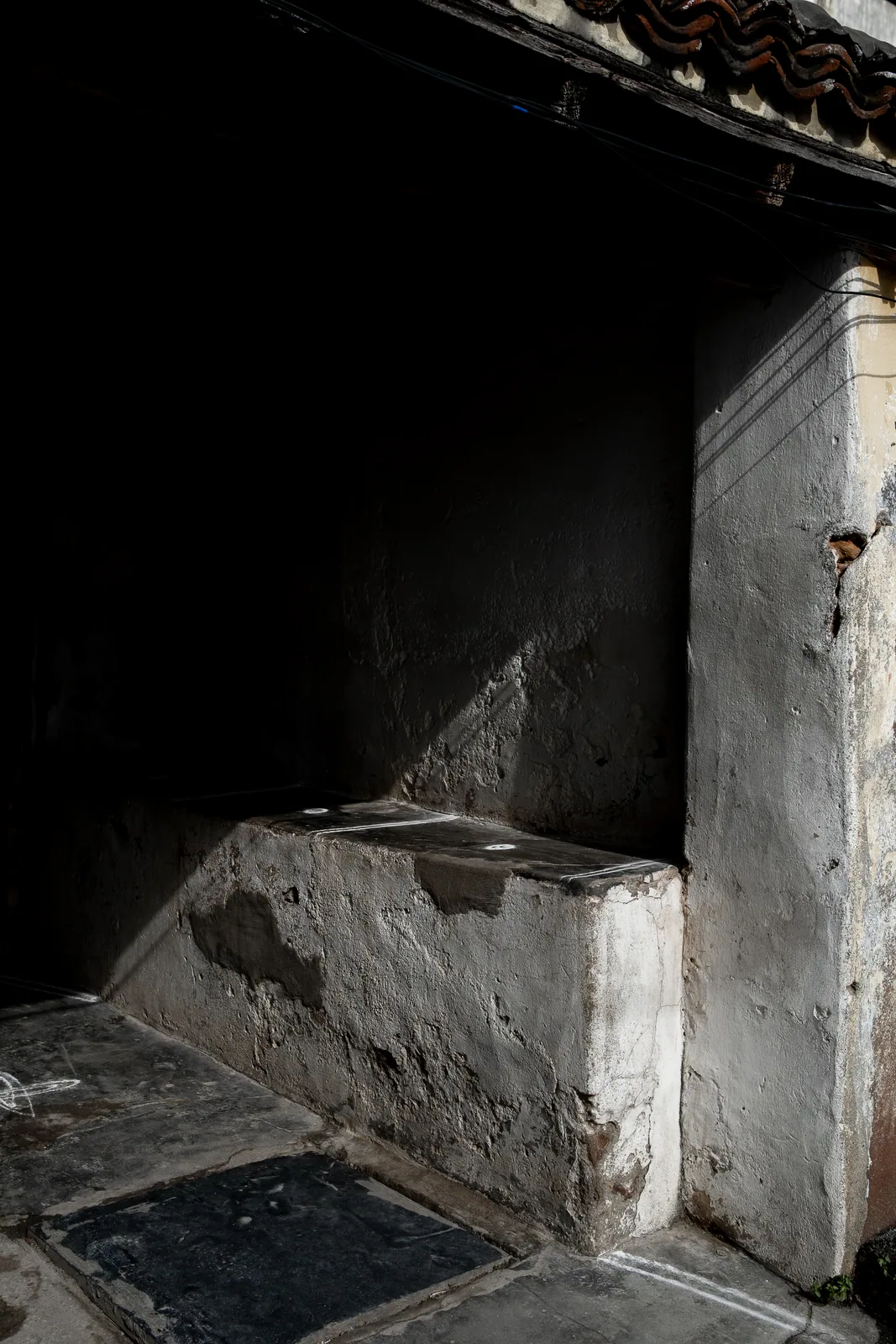 Morning light falls across the raised verandah seat of an old Tamil home and leaves the rest in deep shadow.