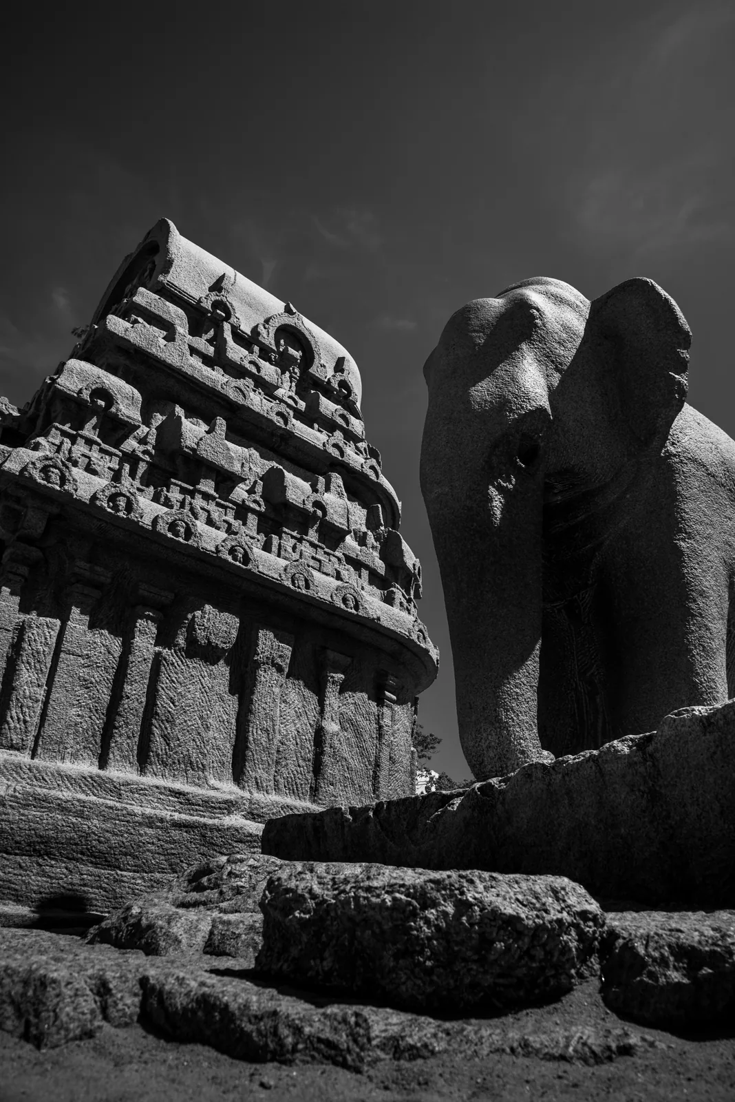 A carved stone elephant stands guard beside a richly sculpted wall.