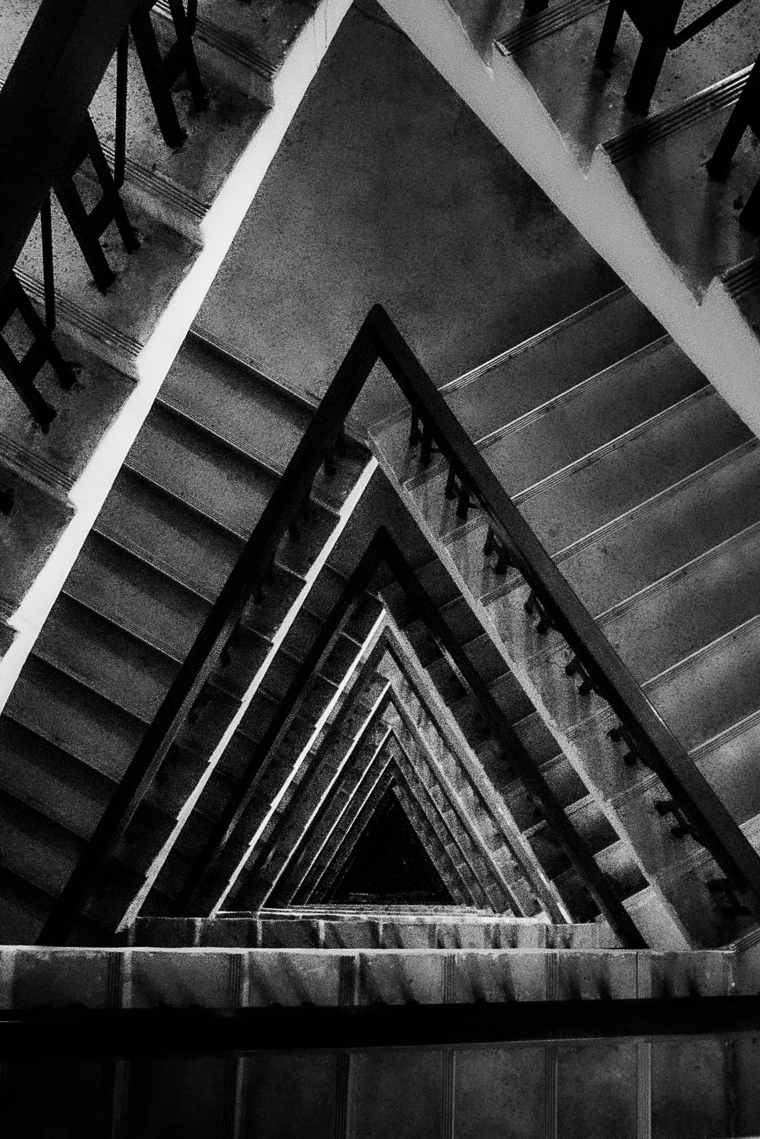A triangular stairwell spirals upward in tight, receding flights.