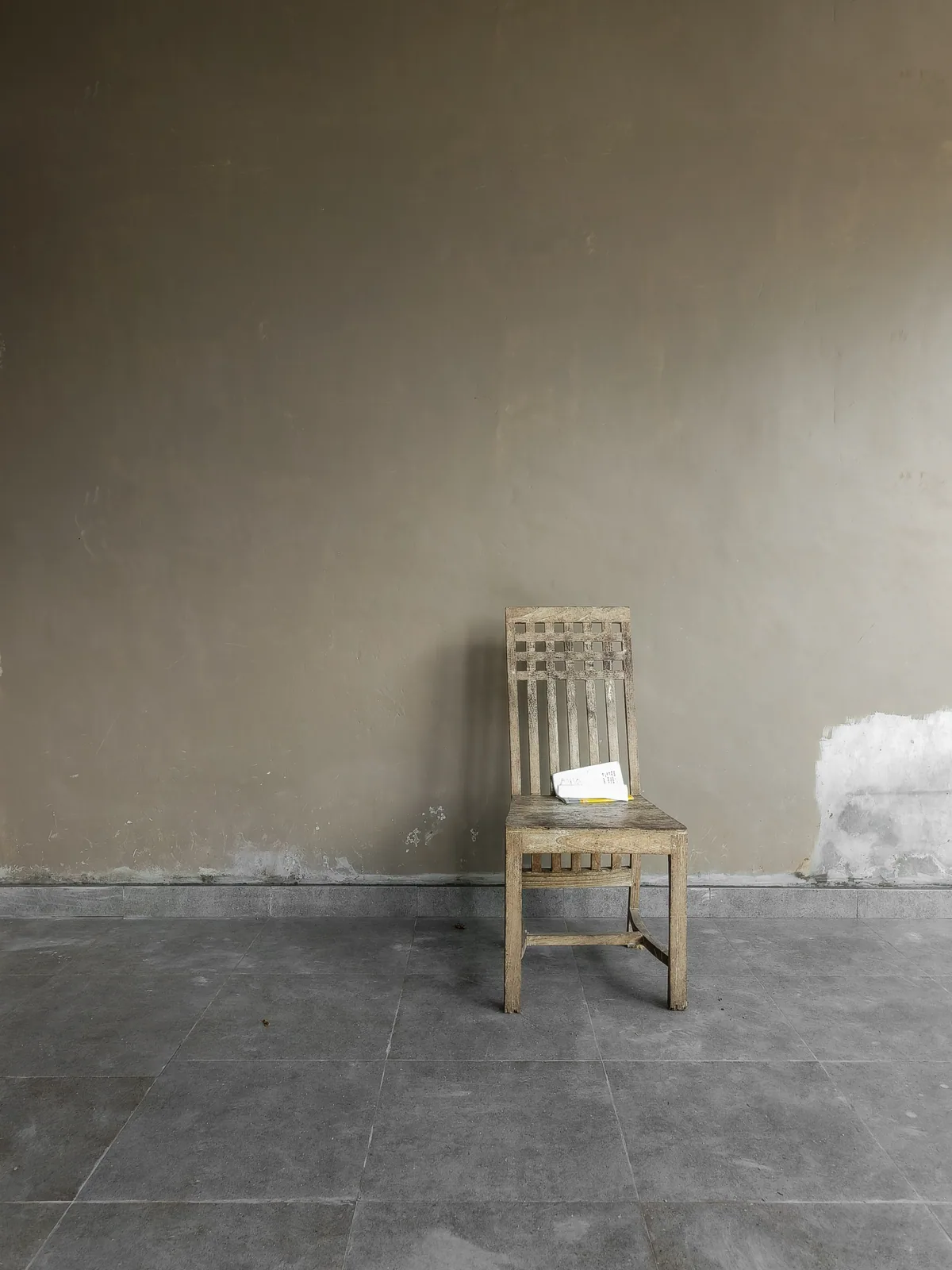 A single wooden chair against a plain wall.