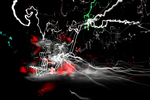 Streaks of white, red and green light scrawl across the dark: a photograph made by movement.