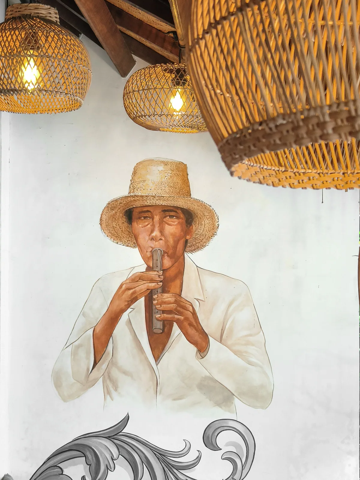 A painted flute player in a straw hat beneath glowing rattan lamps.